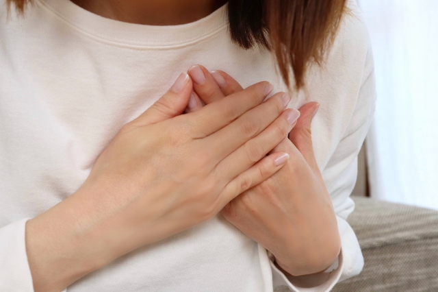 胸を両手で抑える女性