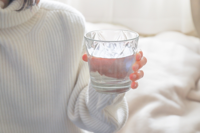 水の入ったコップを持つ女性